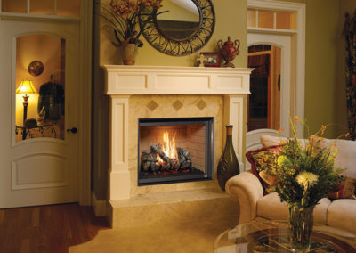 Stock photo of 864 TV 40k CF gas fireplace insert with cream colored marble surround and white mantel with a mirror and other decorations. There is a vase to the right of the fire and a sofa. There are flowers on the coffee table.