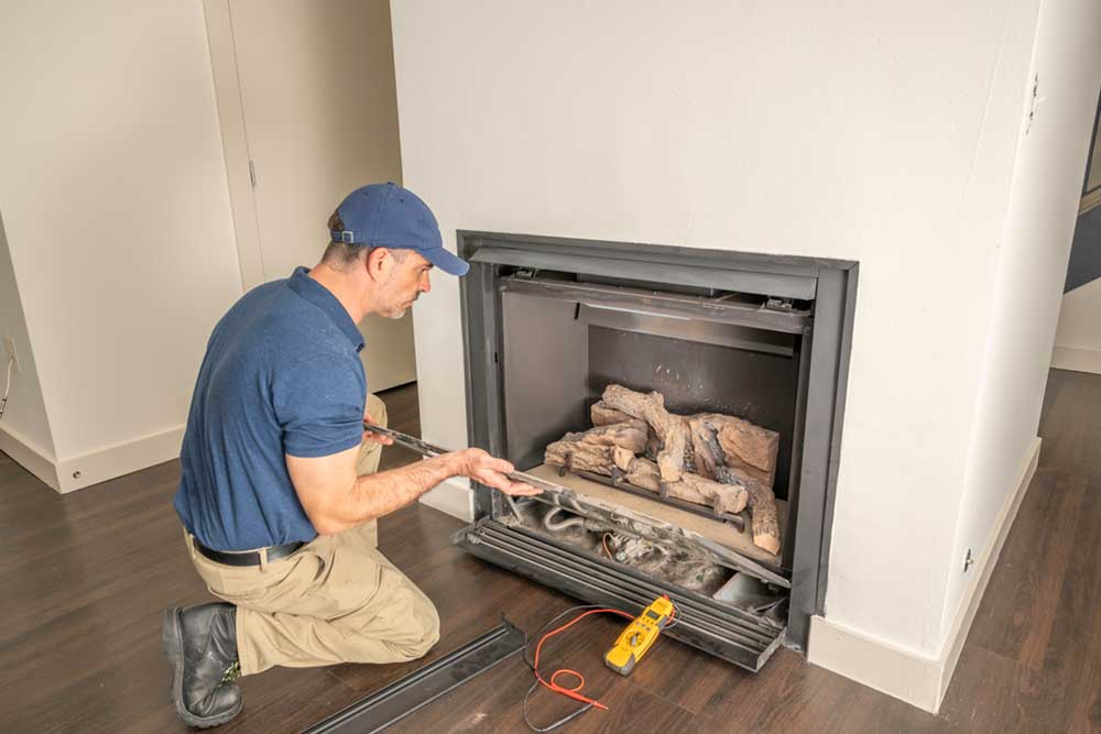 Man kneeling on the ground inspecting fireplace