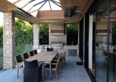 Stock photo of W Series1 outdoor full kitchen with build in grill, table and chairs, and glass roof for lighting during the day.