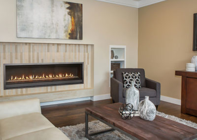 Stock photo of ProBuilder 72 linear gas fireplace with a white sofa and gray chair. Over the fireplace is a modern painting.