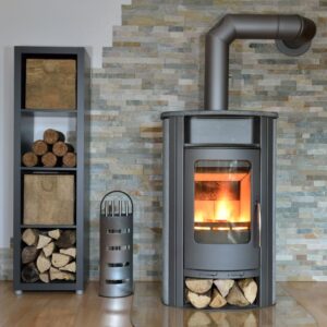 a gray wood stove piped through the wall with a cabinet filled with wood