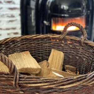 a basket of wood with a wood stove in the background